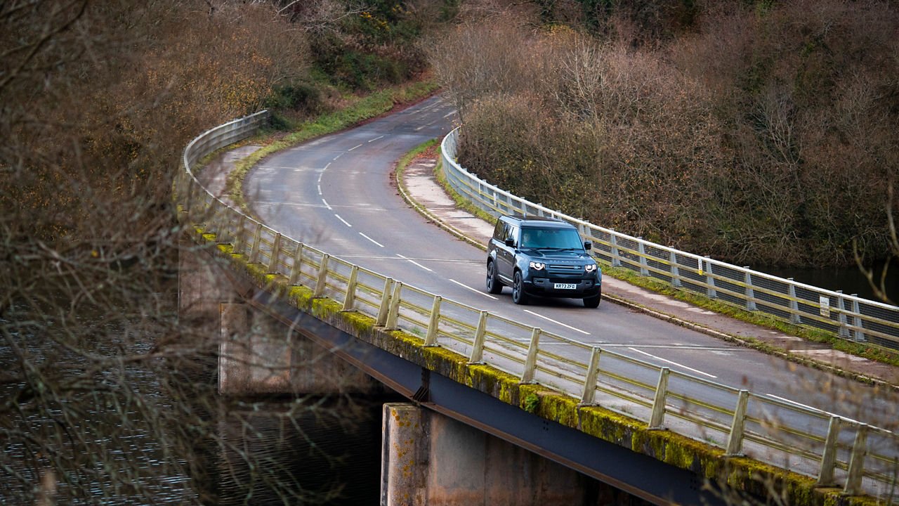 A Defender drives along a bridge over a river