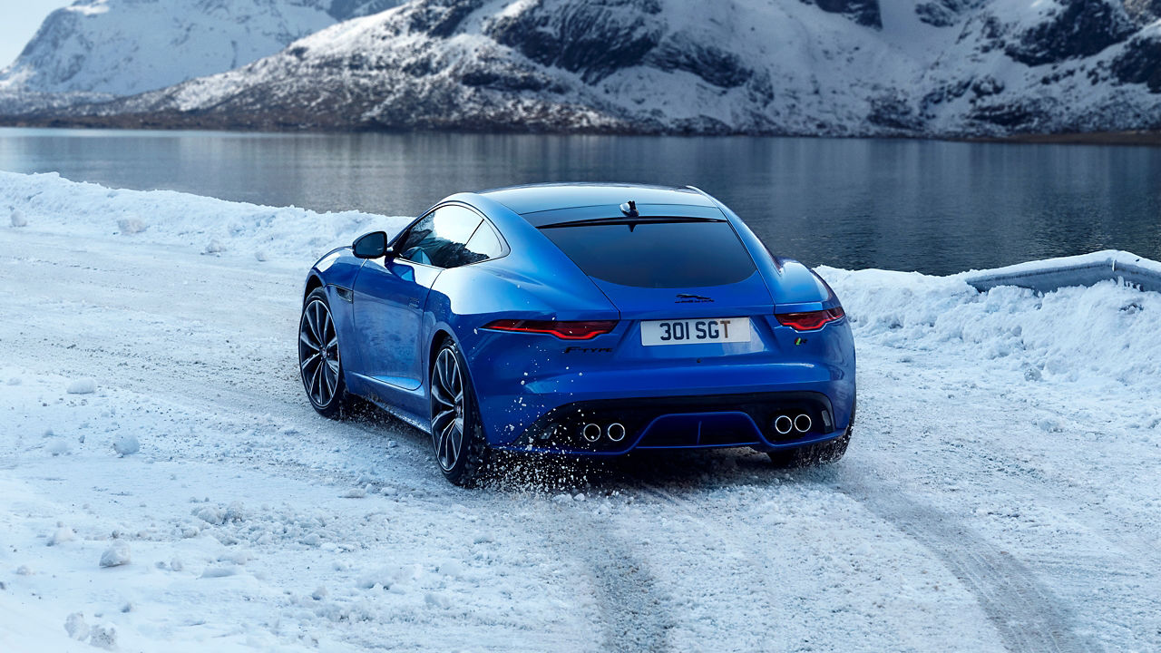 Parked Jaguar F-Type near pond with Snow hill background