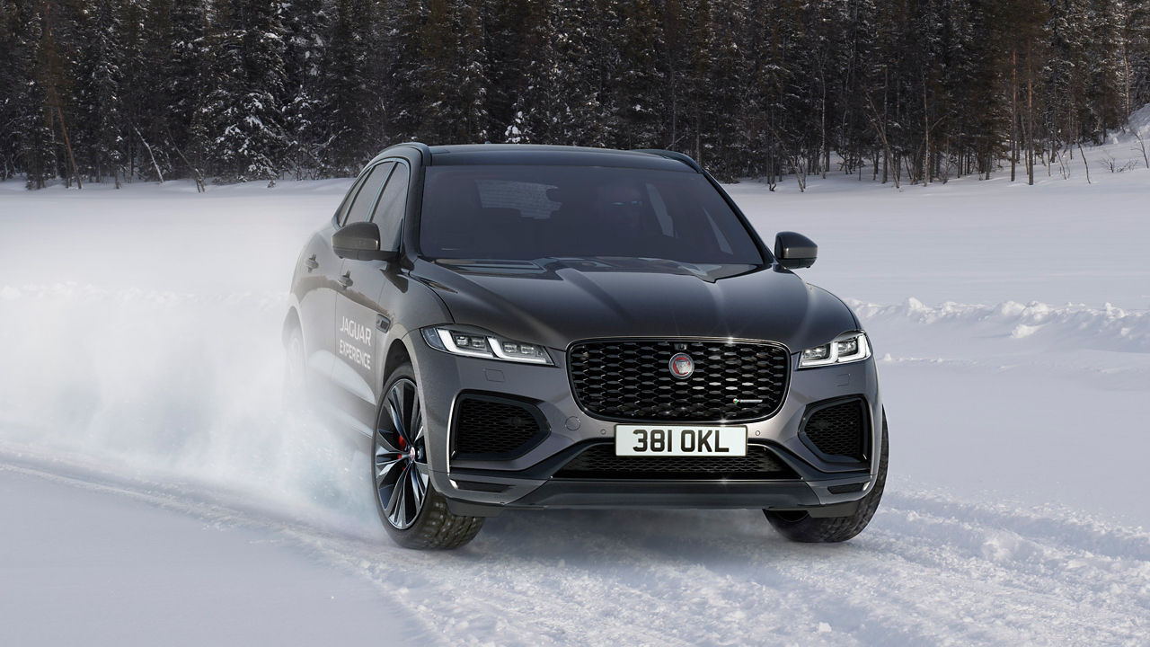 Jaguar passes through a snowdrift and snowy land road at winter