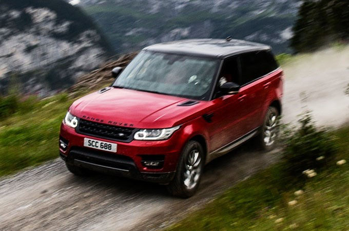 Red Range Rover driving in mountain range