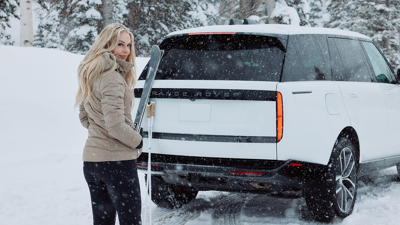 Lindsey Vonn standing with ski gear at Range Rover back