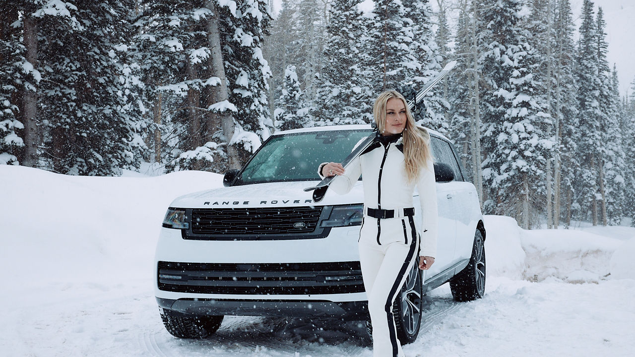 Lindsey Vonn standing in front of a Range Rover with her ski gear