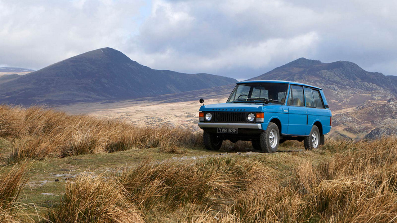 Blue Range Rover driving near mountains