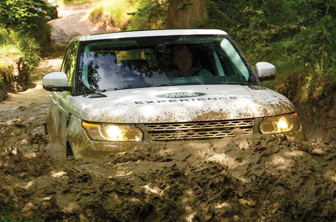 White Range Rover driving through mud