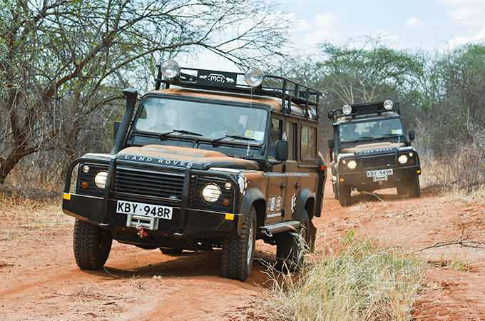 2 Range Rovers driving through rough terrain