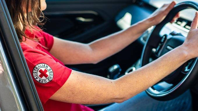 Australian Red Cross employee sitting behind the wheel of a Land Rover vehicle