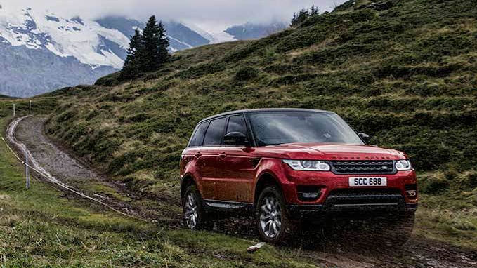 Red Range Rover driving through dirt and mountain