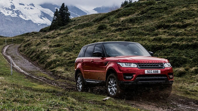 Red Range Rover driving through dirt and mountain