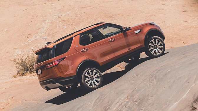 Land Rover Discovery in orange parked on a rock