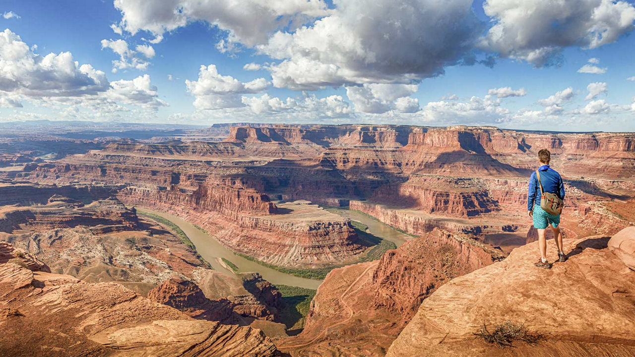 individual stepping on a rock enjoying the view of a canyon