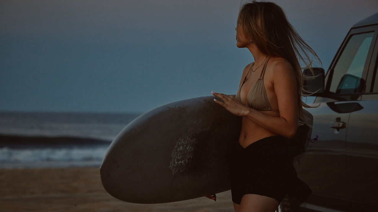 car on beach with surfboard