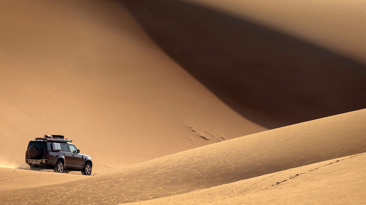 Defender driving through desert in Dubai