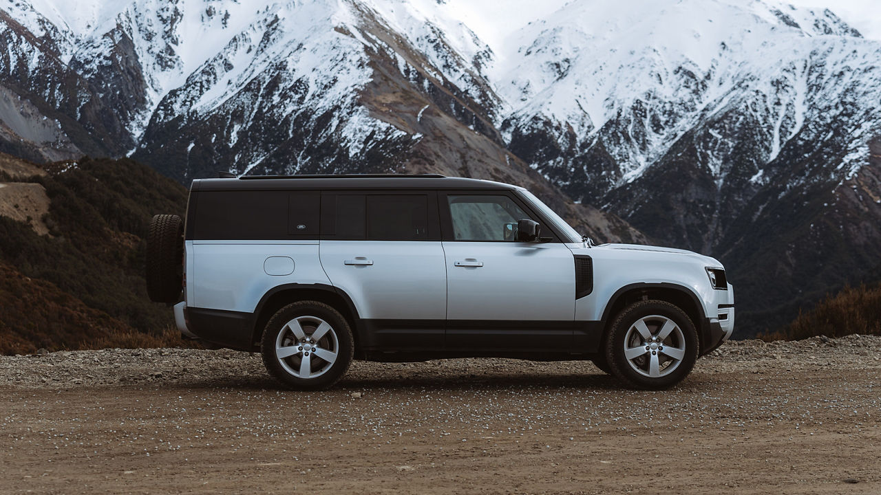 Defender 130 parked infront of Snowy mountains