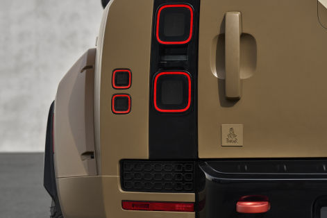 Close-up of a Defender SUV rear corner, featuring distinctive square LED taillights, rugged bodywork, and an embossed Defender emblem.
