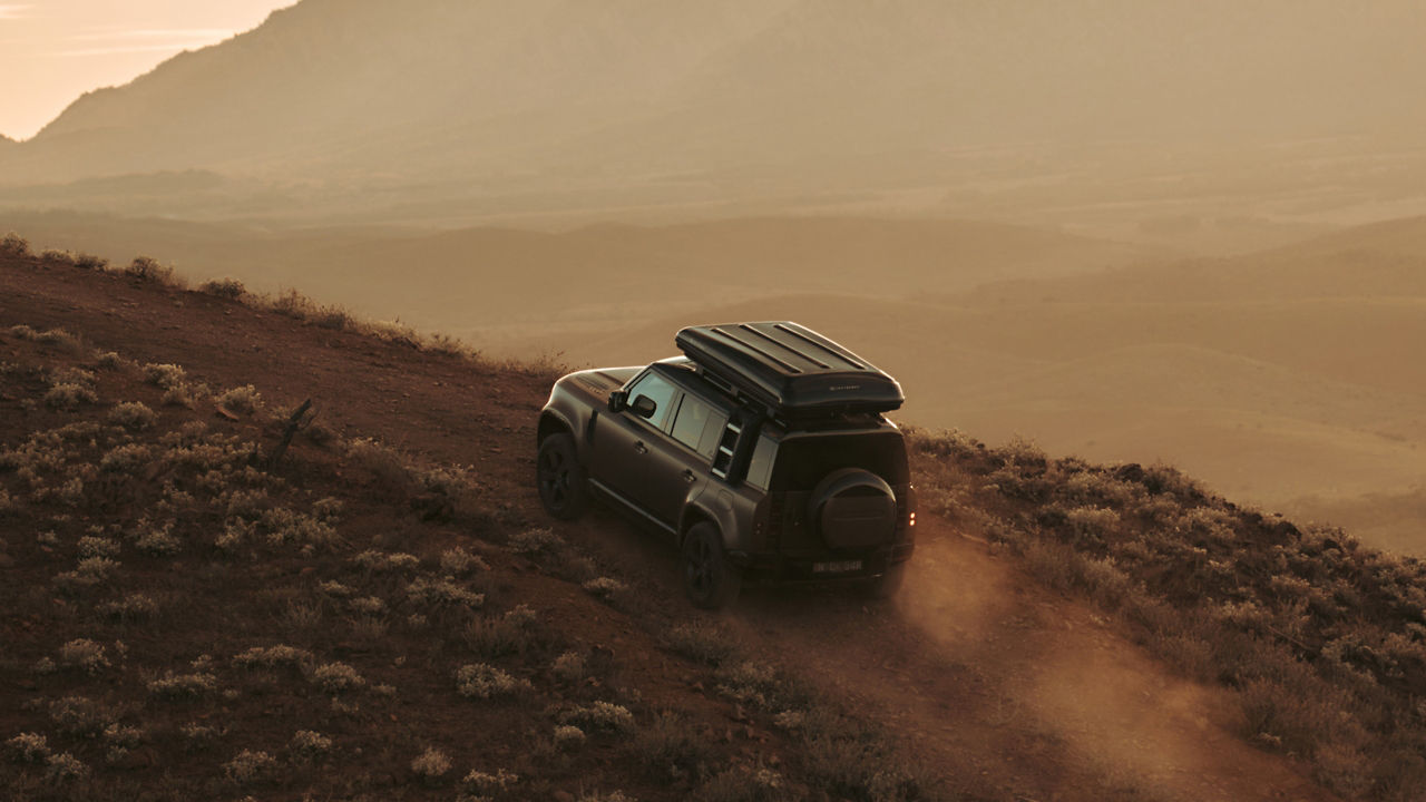 aerial view of Defender on a dirt road at sunset