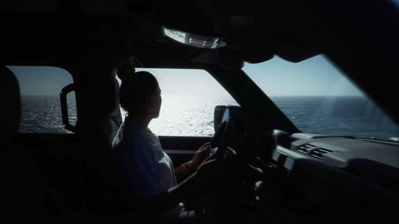 woman inside defender looking at the sea through the window