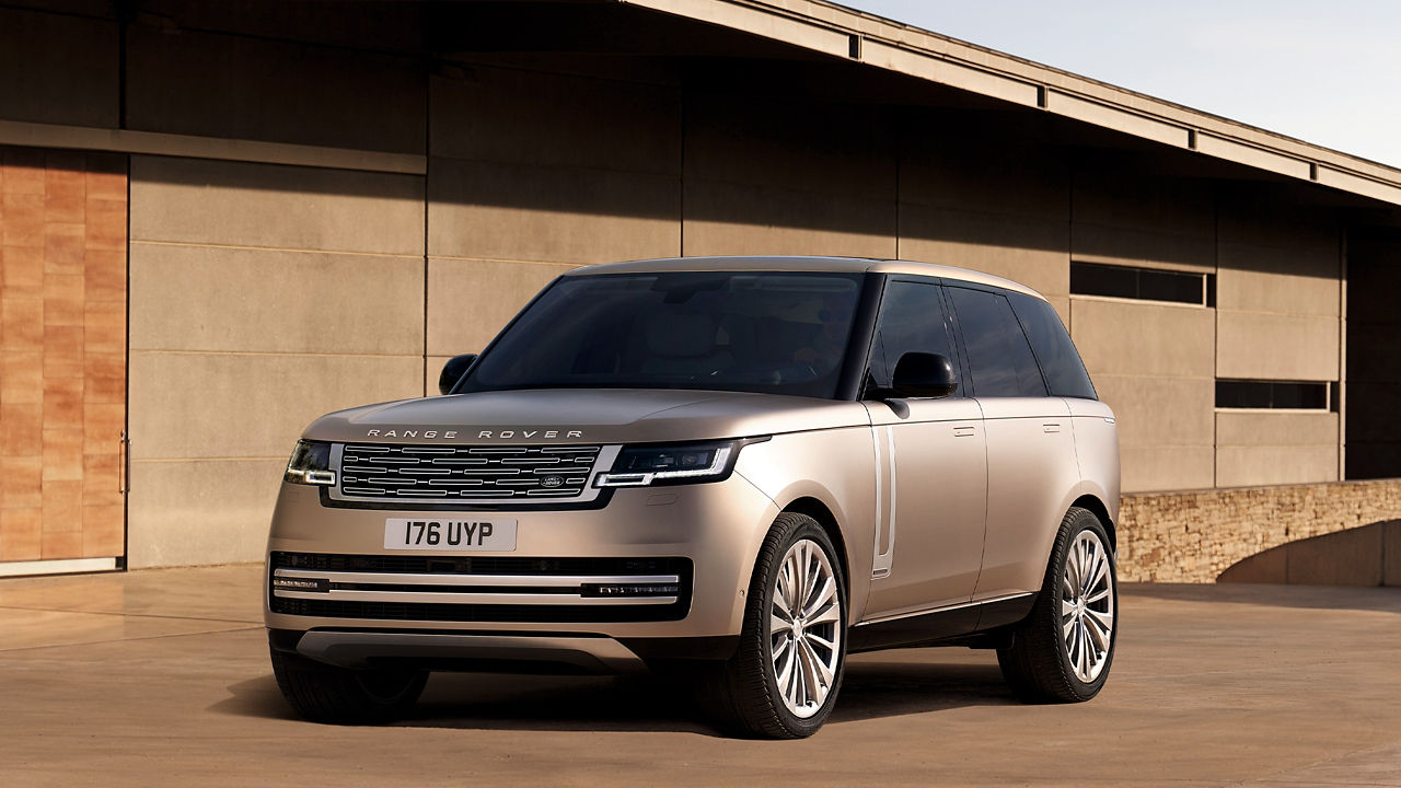 Range Rover in Sunset Gold parked outside of contemporary building.