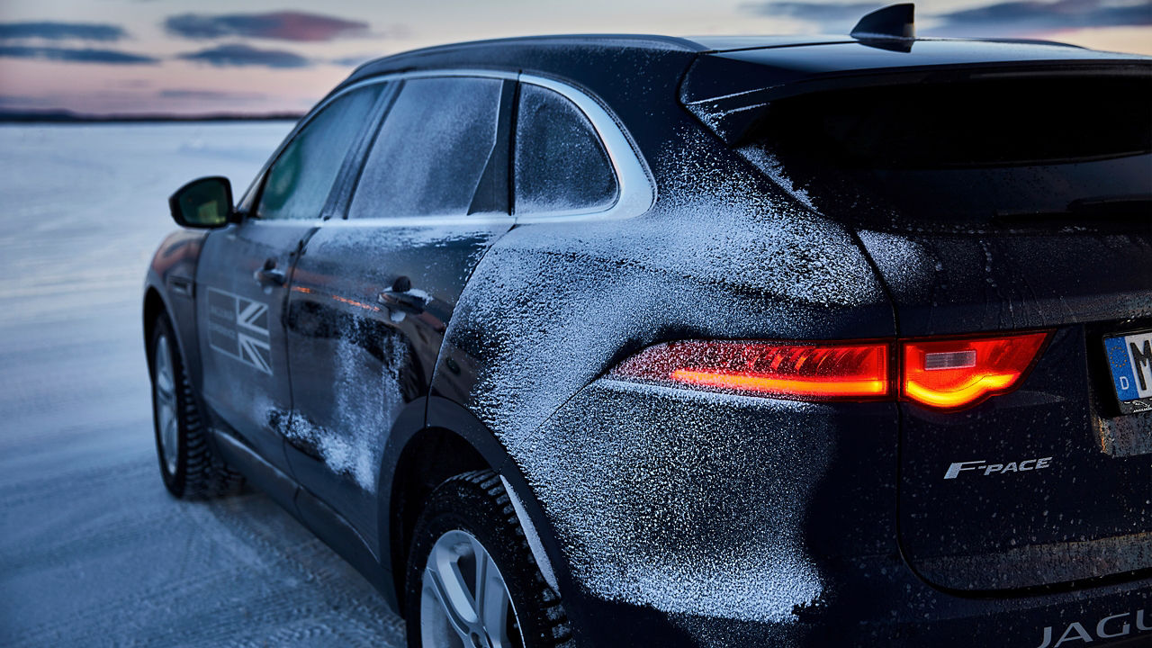 Jaguar car parked on snowy landscape, winter, back side view