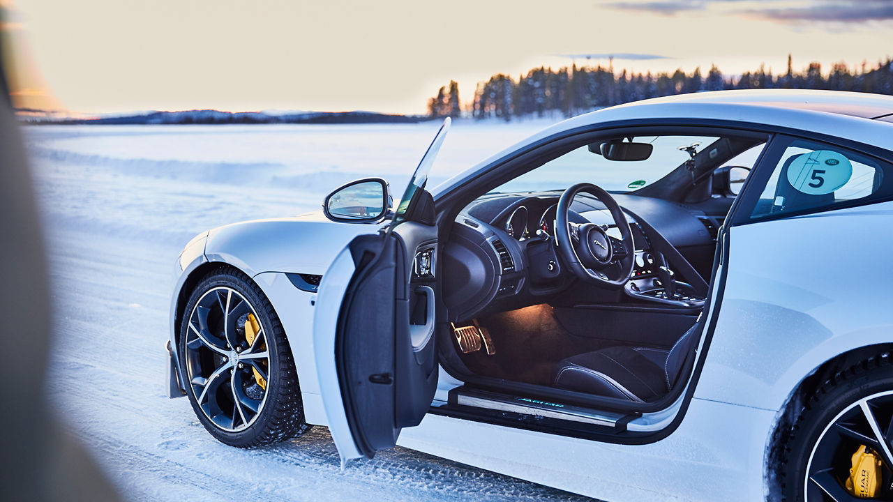 Jaguar car parked on a snow-capped road and open door