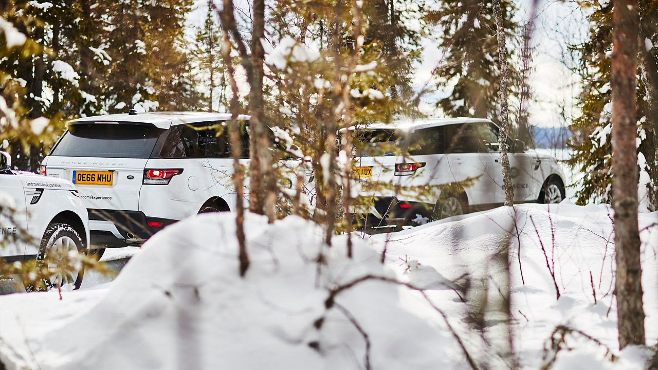 Range Rover car on winter road and snow splash backside view