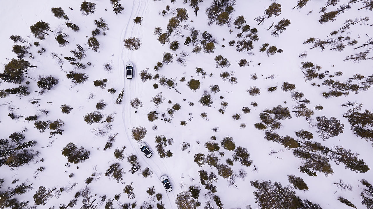Aerial view of Range Rover cars going on frozen rural road on winter