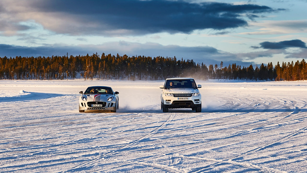 Jaguar and Range Rove Driving a race on a snowy landscape road