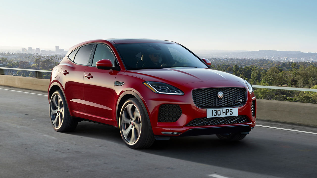 Jaguar car on asphalt road with hill background