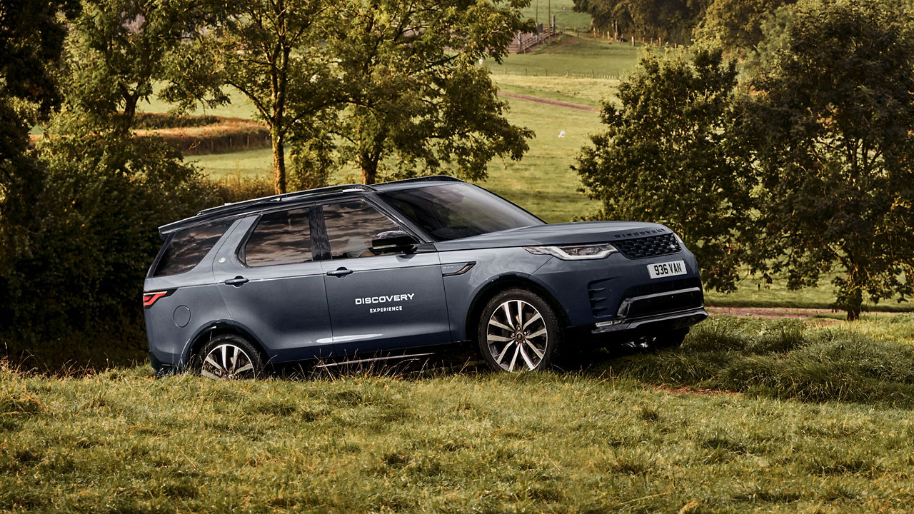 Discovery parked on grassy terrain with trees in background.