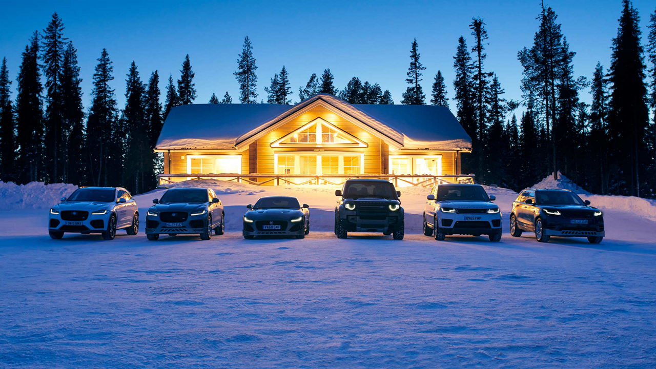 Jaguar Land Rover family of vehicles parked in front of a snow lodge