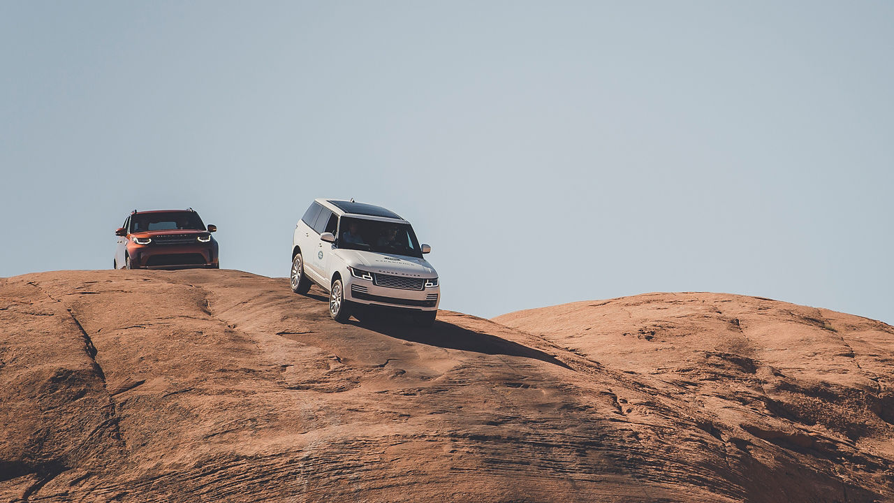 Range Rover cars moving down into the mountains with the help of the instructor