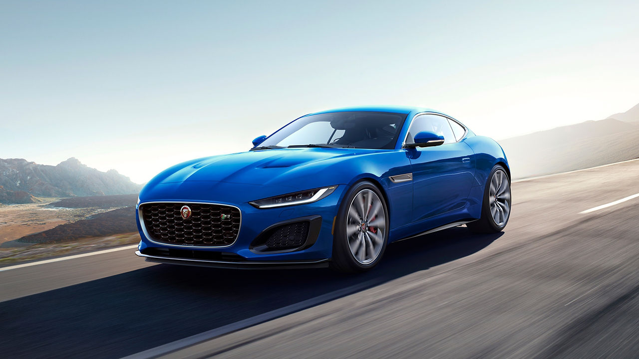 Jaguar F-TYPE running on the hill road surrounded with mountain at background 