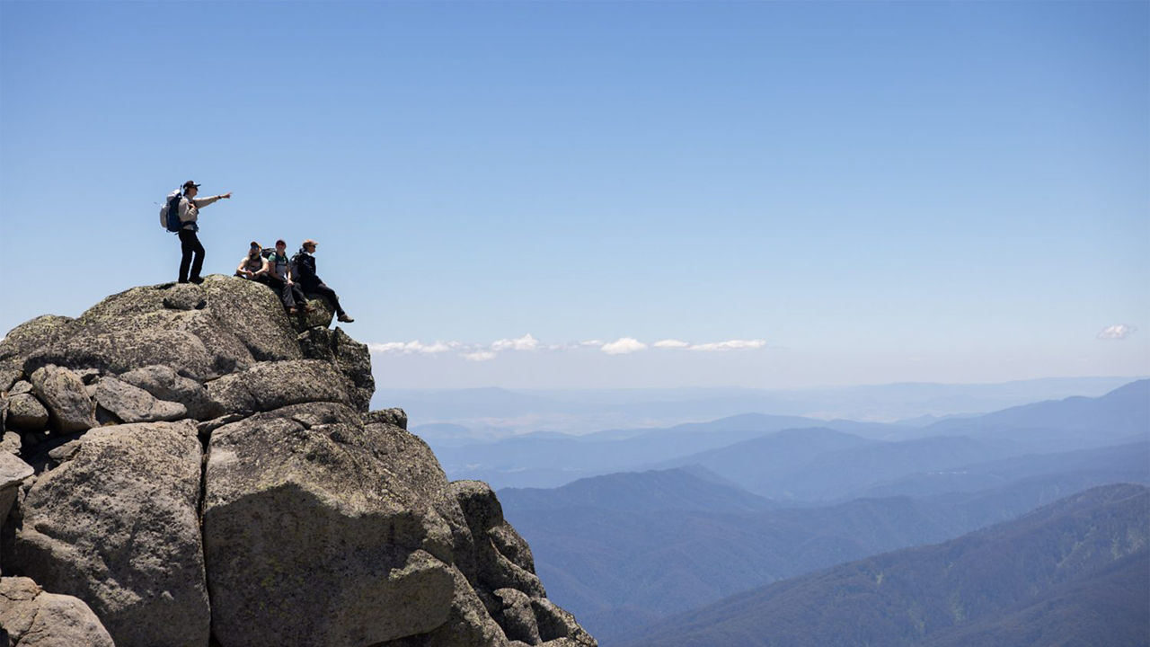 a guy standing top of the mountain 