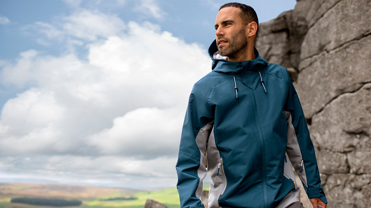 Male model on rocks looking to side wearing softshell jacket