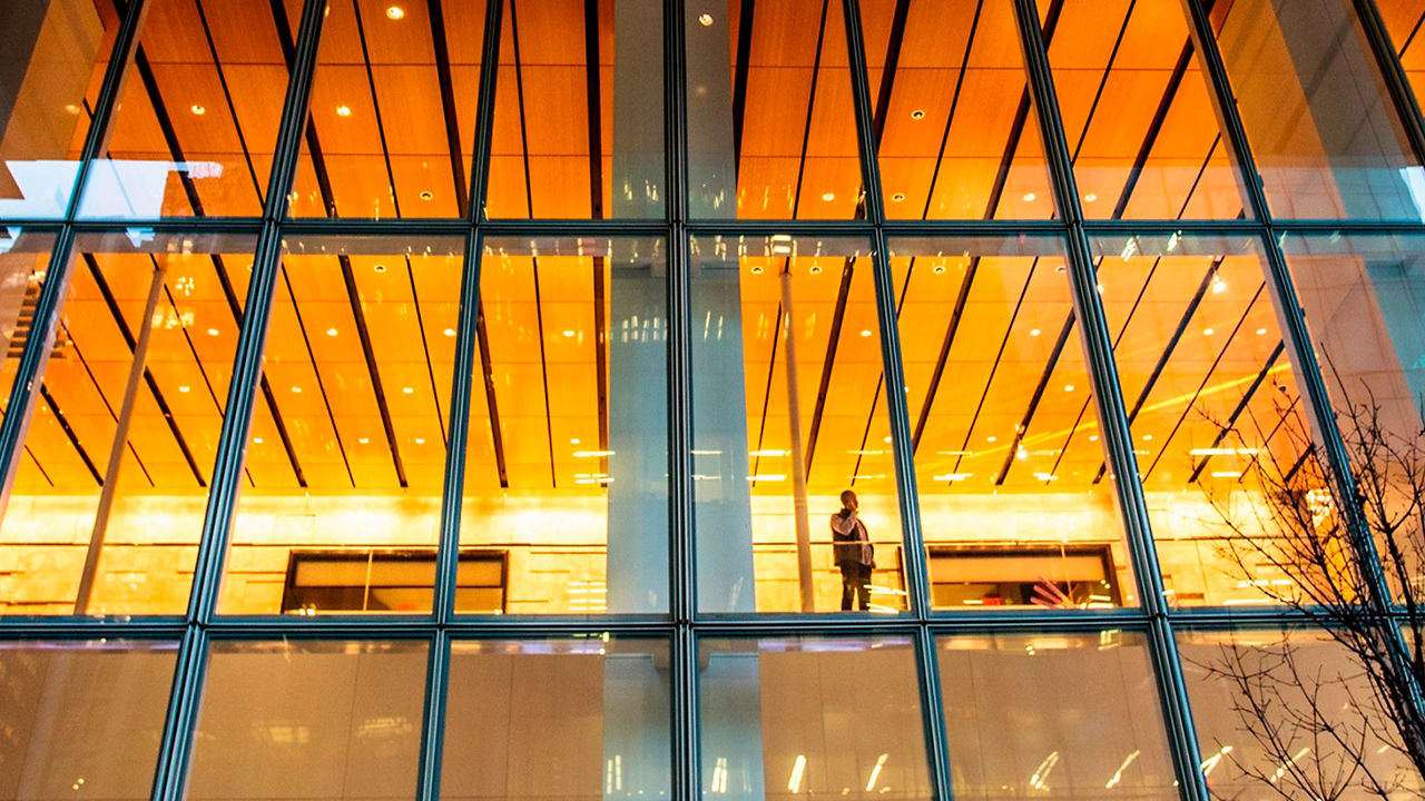 A man talking on phone standing near glass of building