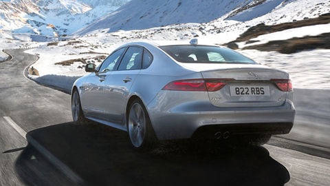 Jaguar XF running on hill road filled with snow