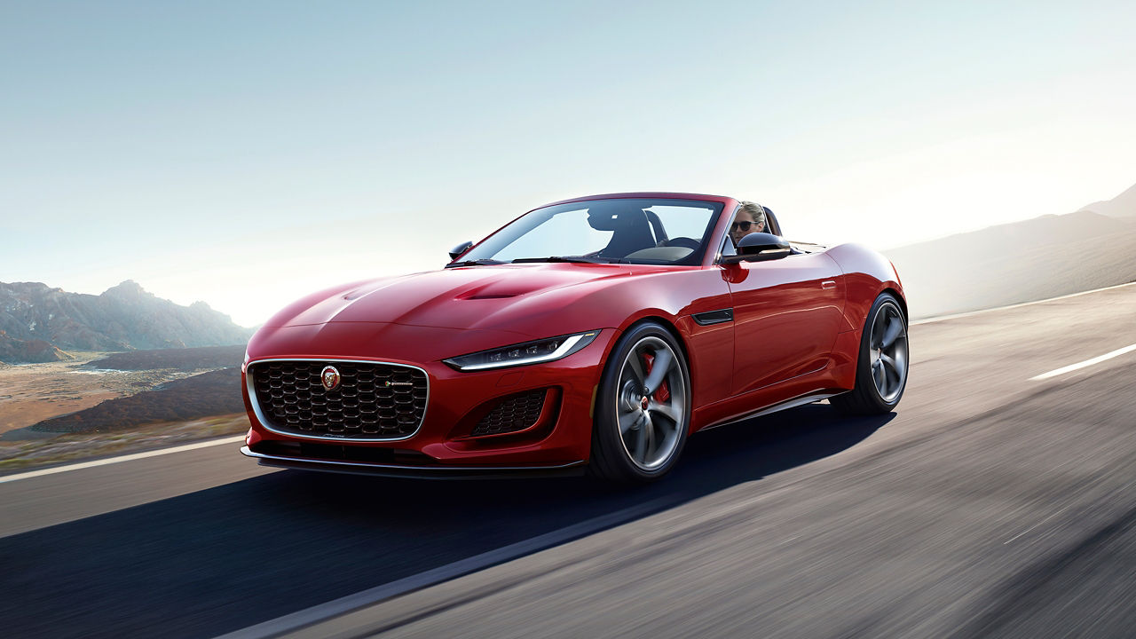 Jaguar F-Type running on hill road surrounded with mountains