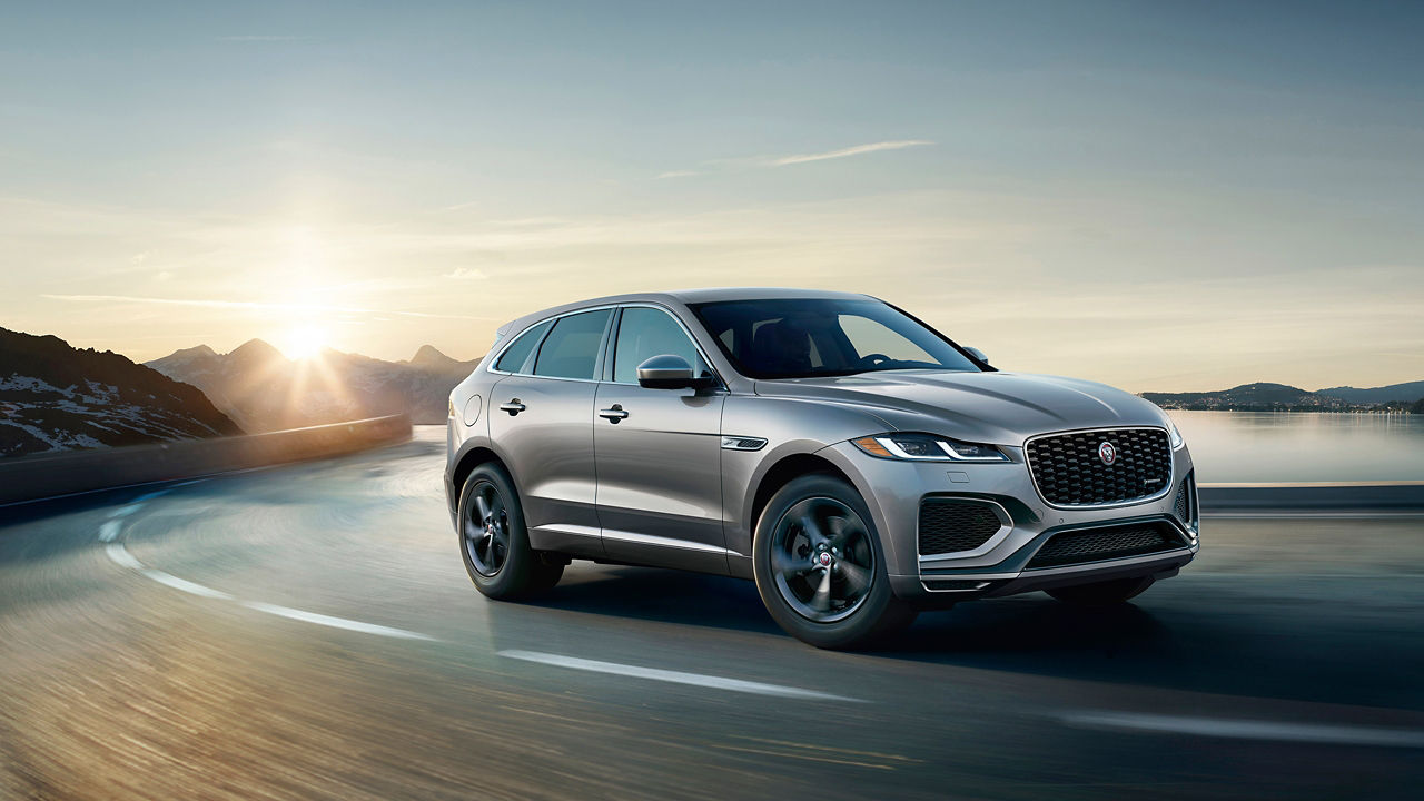 Jaguar F-PACE running on river side road surrounded by mountains 