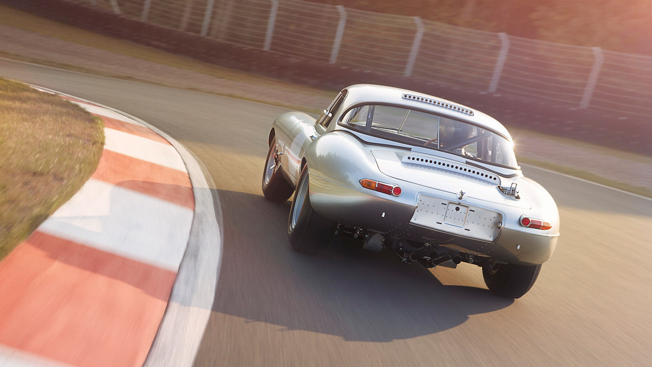 Jaguar E-Type car running on the road, back view