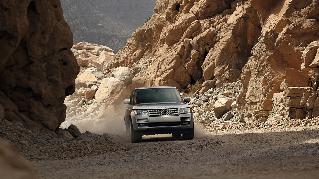 Range Rover Driving On Stone Road With A Mountain In Background