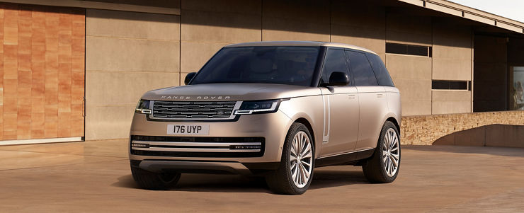 Range Rover in Sunset Gold parked outside of contemporary building.