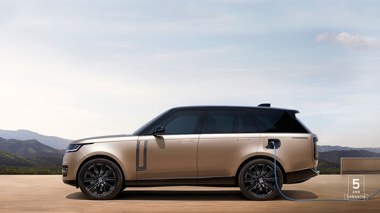 Side view of Range Rover PHEV in Sunset Gold charging batteries with 5 years warranty watermark.