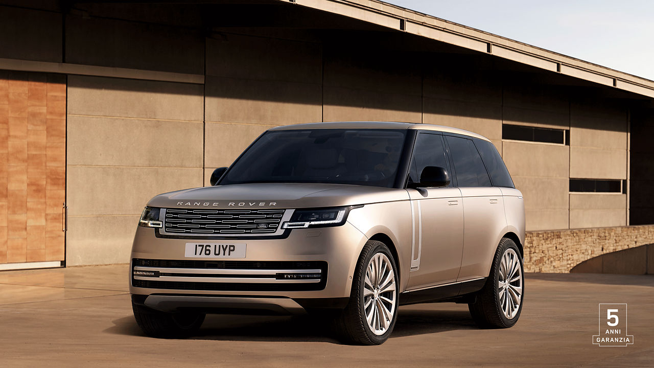 Range Rover in Sunset Gold parked outside of contemporary building with 5 years warranty watermark.