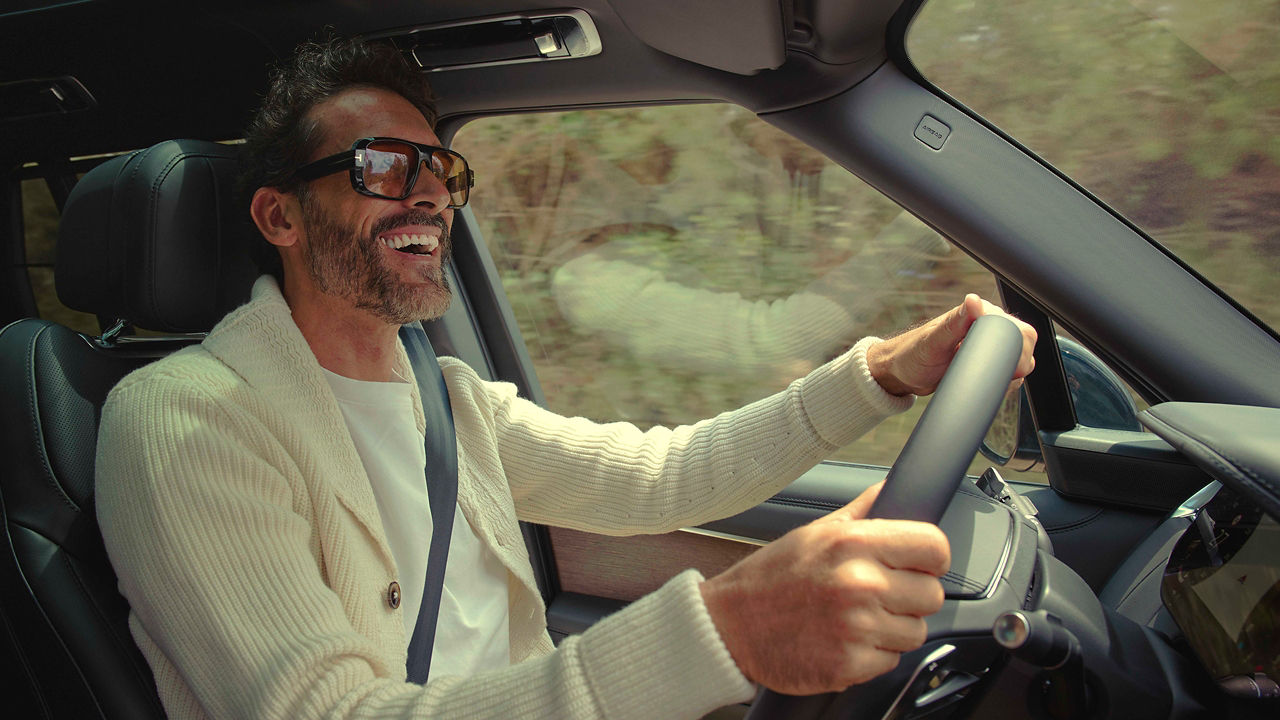 Person driving a Range rover on a road lined with trees.