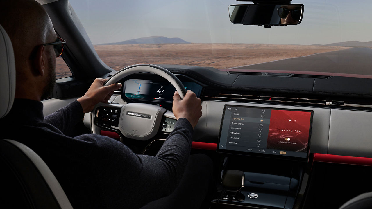 Man driving Range Rover Sport on open road, dynamic mode on screen