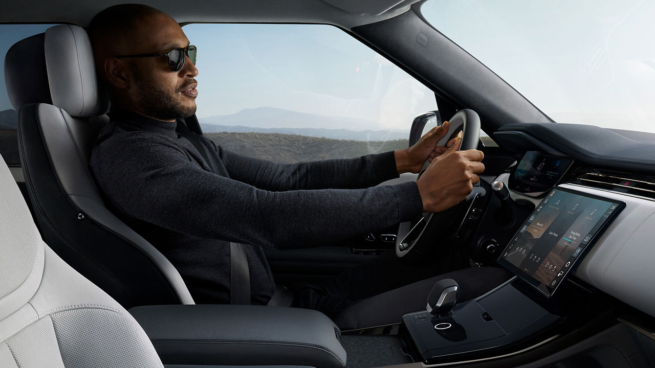 Side view of man on driving seat of Range Rover Sports 