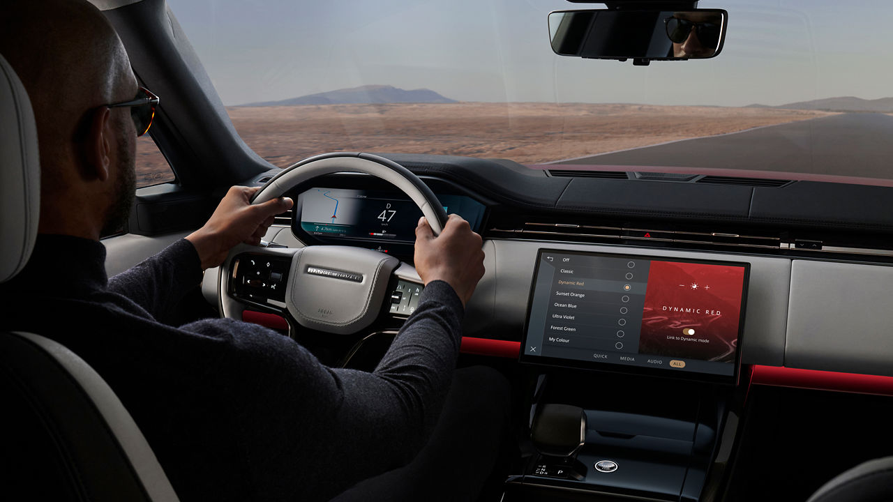 Range Rover Sport steering wheel and infotainment system while a man is driving.