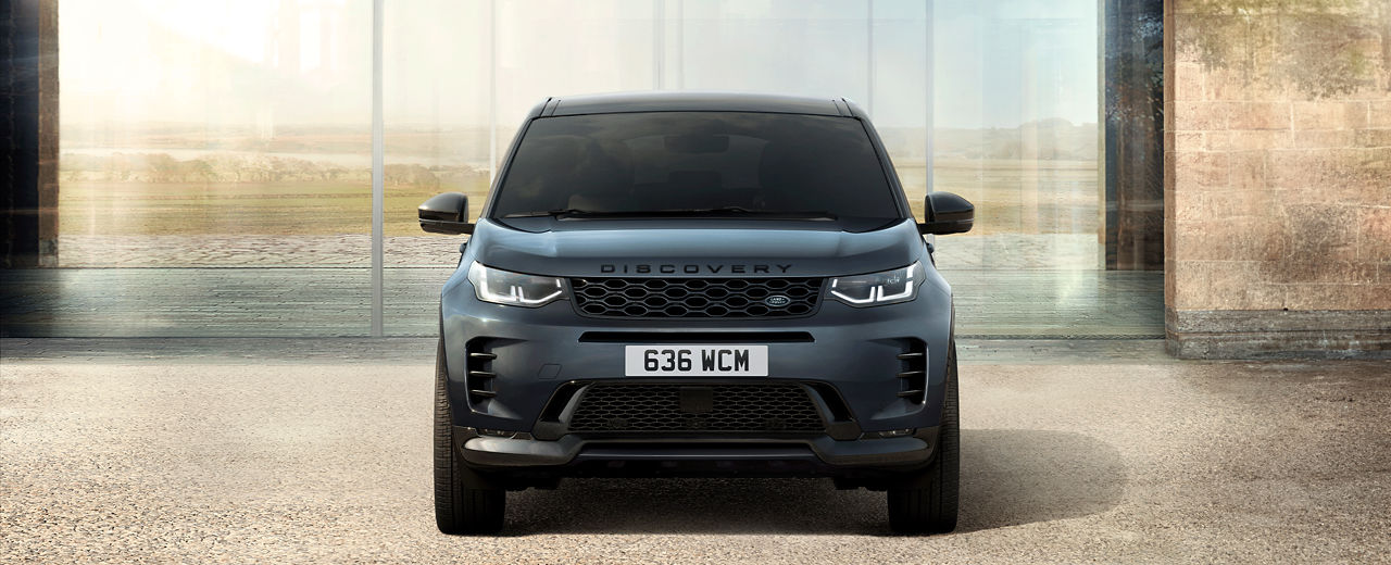 Front view of Discovery Sport in Varesine Blue parked outside of a contemporary building.