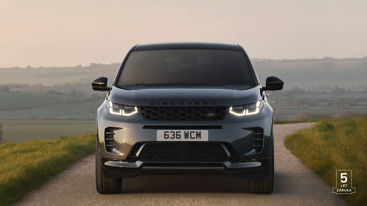 Front view of Discovery Sport driving on a rural road with 5 years warranty watermark.