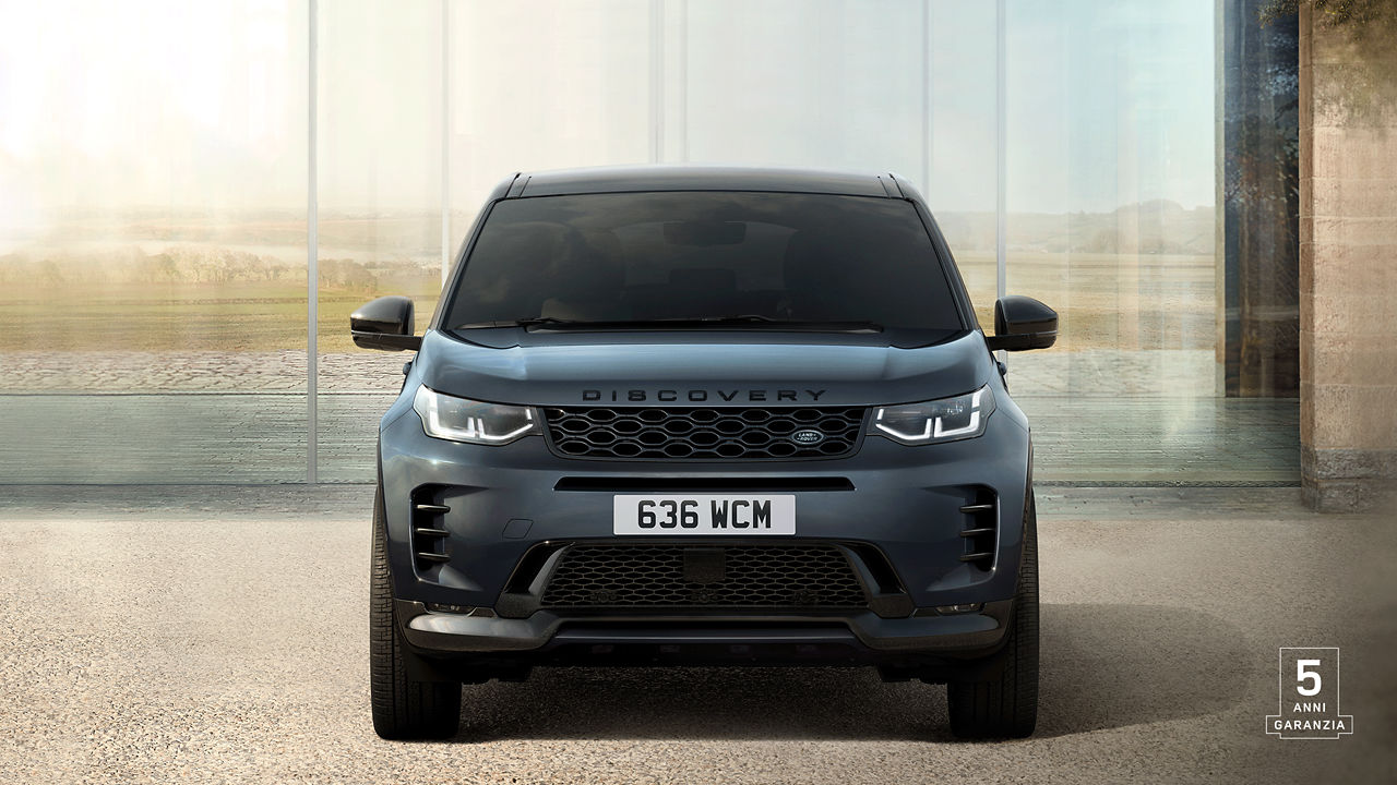 Front view of Discovery Sport in Varesine Blue parked outside of a contemporary house with 5 years warranty watermark.