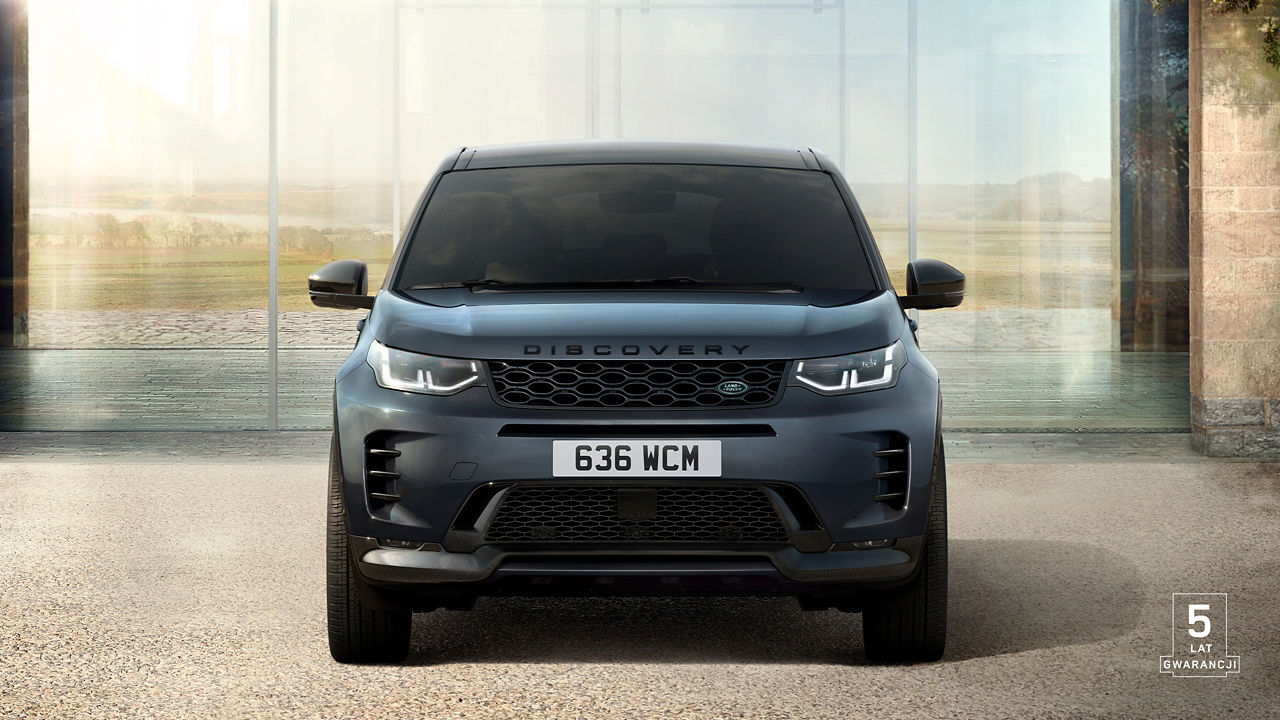 Front view of Discovery Sport in Varesine Blue parked outside of a contemporary house with 5 years warranty watermark.